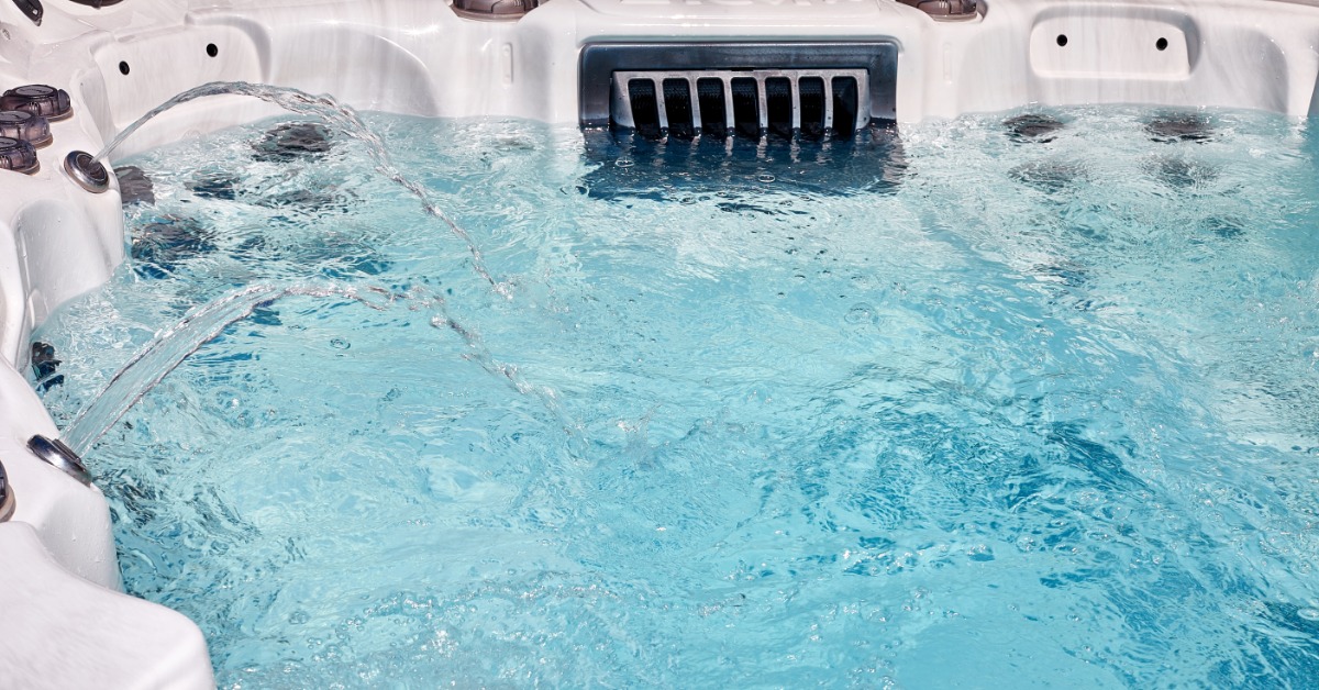 A white hot tub filled with clear blue water, showing active jets circulating and bubbling water inside.
